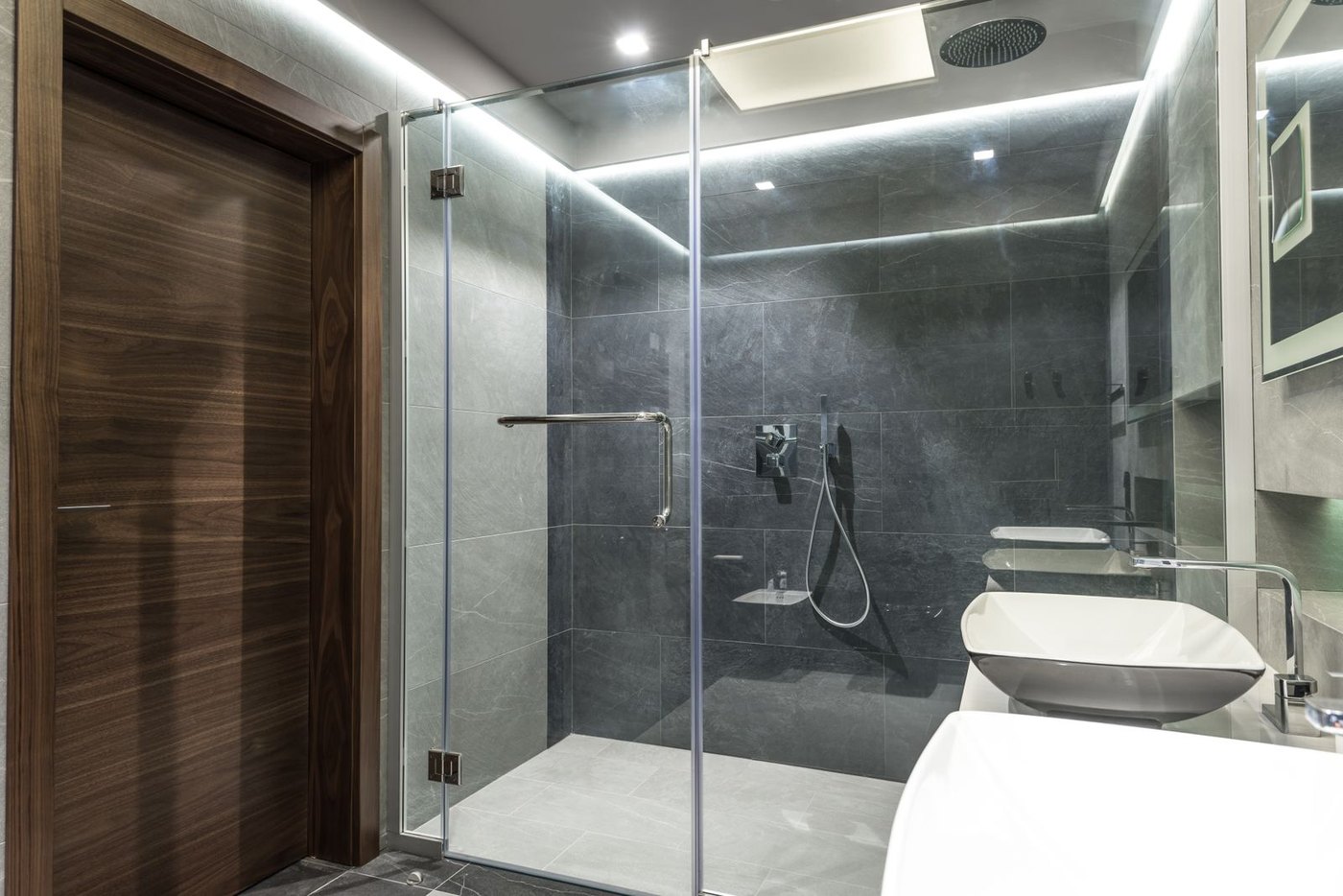 Dark-tile walk-in with a hinged frameless door - hinges and patch fittings carry the 10 mm leaf.