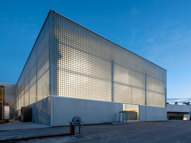 Glass block as luminous masonry: a full facade that glows softly by day and becomes a lantern at night.