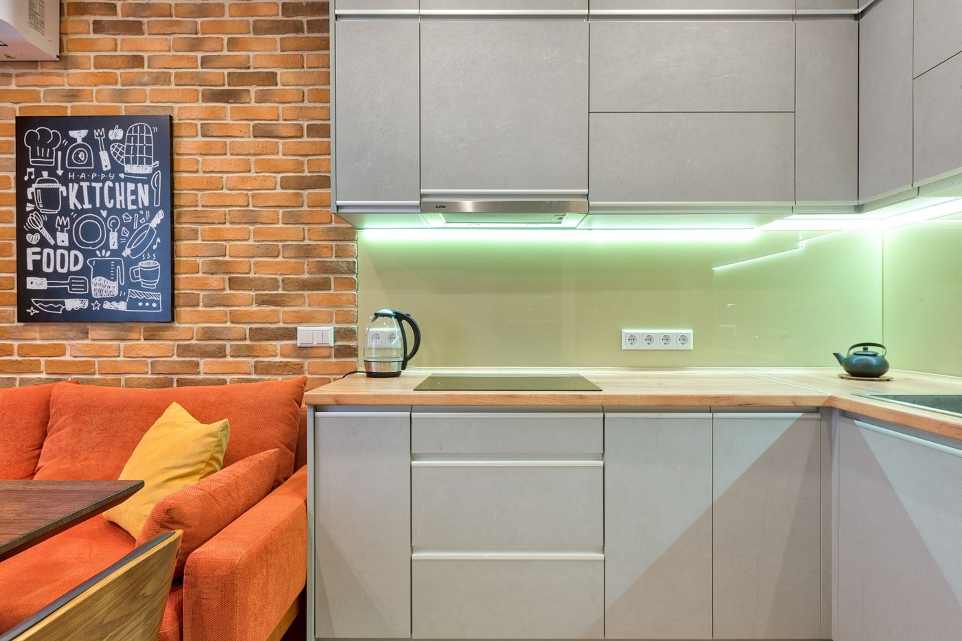 Back-painted glass splashback in a working kitchen: seamless, wipeable and color-stable under heat.