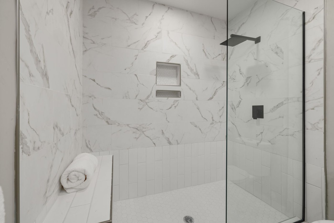 A frameless walk-in in a marble bathroom: one fixed 10 mm panel does all the work.